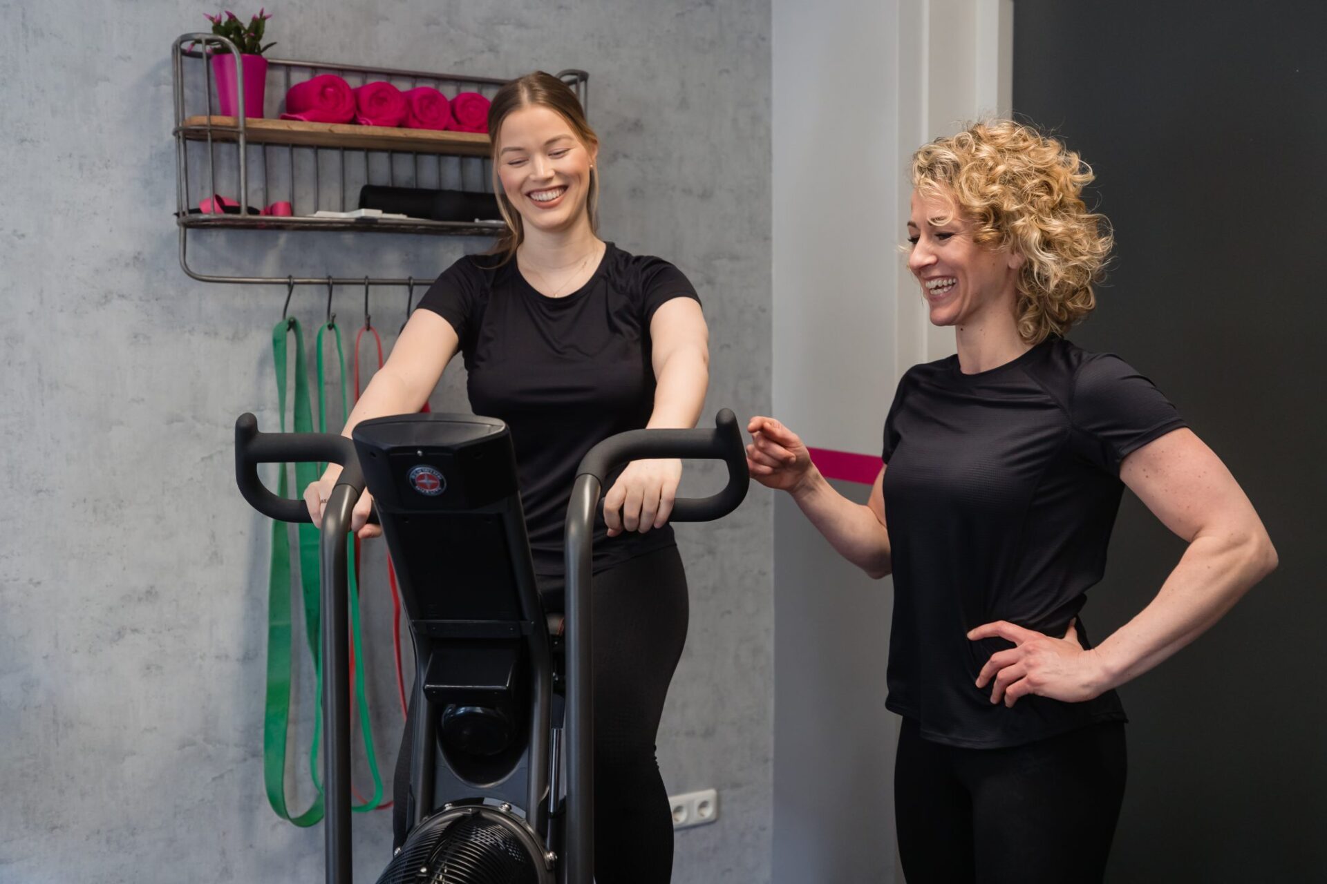 Vrouw die op de assaut airbike zit met personal trainer Kirsten Boersma voor vrouwen